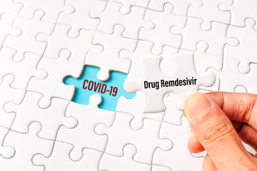 The drug remdesivir word on white jigsaw puzzle go to replace COVID-19 word on blue gap - idea answer concept.