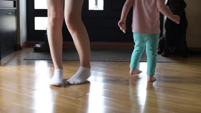 legs of mom and daughters who dance in the hallway of the house on a weekend. Close up, no face
