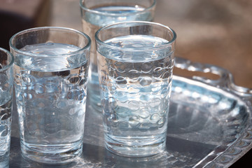 Glasses of water are on a metal tray