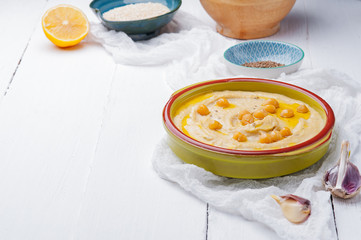 Bowl of arabic or lebanese vegetarian hummus.in green bowl on a white wooden background. Traditional Middle eastern hummus. Healthy eating concept,