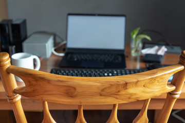 Casual work space at home. Focus on the back of a chair.