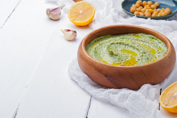 Hummus with spinach in a wooden bowlon a white wooden background. Traditional Middle eastern hummus. Healthy eating concept,