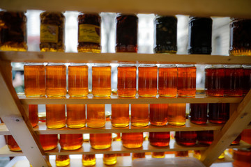Shallow depth of field (selective focus) image with jars full of honey on sale in a traditional...