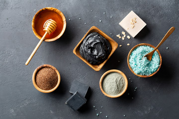 Spa. Natural cosmetics for the body and face. Blue sea salt with seaweed, soaps of herbs and dead sea mud, ground coffee scrub, honey, clay on a dark table. Top view. Copy space.