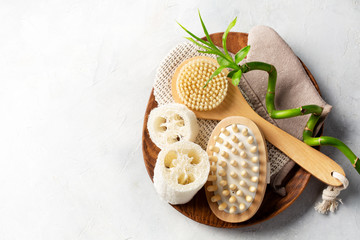 Spa or bathroom concept. Brush and glove for body massage, loofah washcloth on light background. Top view. Space for text.