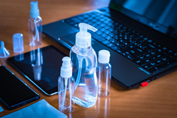 Various bottles with a dispenser on the table. Concept - an antiseptic is next to a laptop. Concept - disinfection gadgets. Cleaning bacteria after visiting the street. Using a sanitizer at work.