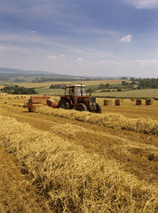 Old image of Straw bailing by an old vintage tractor in Somerset , UK