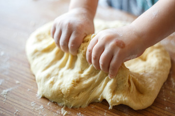Child's hands knead yeast dough closeup