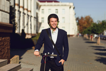 Young man in a helmet rides an electric scooter on a city street in summer