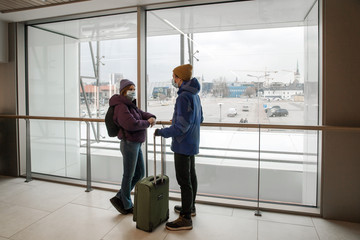 Man and woman with medical face masks are standing in a terminal