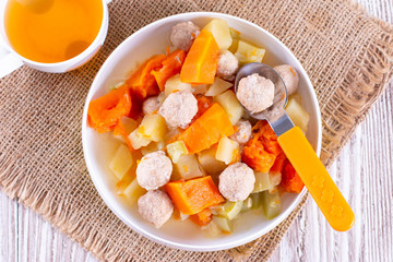 Stewed vpumpkin, potatoes, zucchini and meatballs as dinner for baby. Baby food in children's dishes