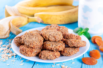 Oatmeal pastry with banana and dried apricots on a blue wooden background. Healthy breakfast concept.