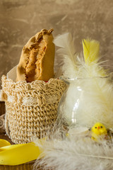 The image shows a typical Easter panzerotto from Campania inside a beige crochet basket with yellow and white feathers on dark wood and gray background