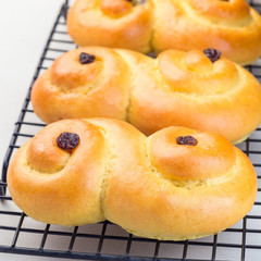 Swedish and scandinavian Christmas saffron buns Lussekatter on cooling tray, light gray concrete background, square format