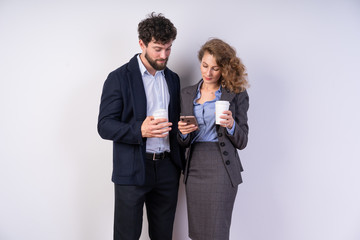 Business people drinking coffee together and at the same time look at the phone, read the news