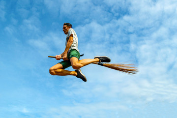 Young man flying on the broom in the blue sky of Siquijor
