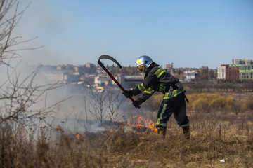 The grass burns in the field Fireman works.