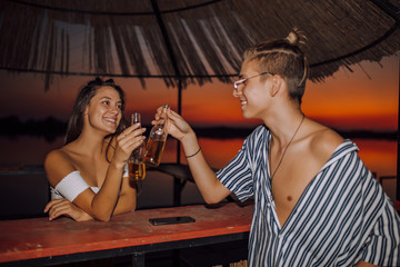 Fototapeta na wymiar Young couple relaxing at the beach bar together, having drinks.