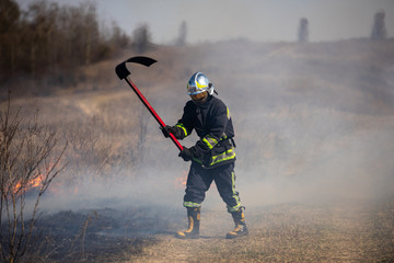The grass burns in the field Fireman works