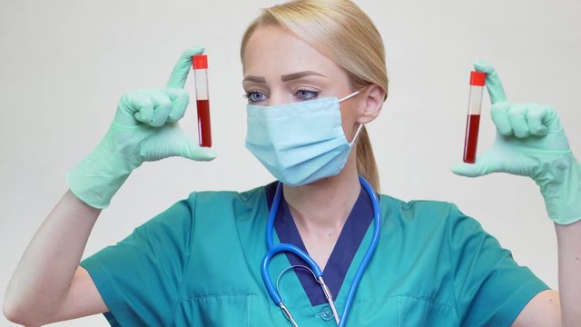 medical doctor nurse woman wearing protective mask and latex gloves - holding blood test tube
