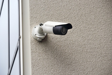 Outdoor video security camera on concrete wall on building corner