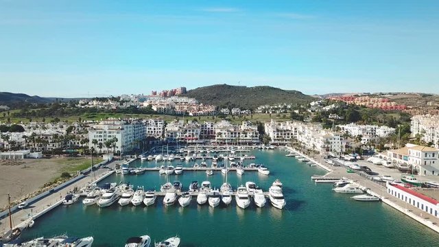 Beautiful Aerial panoramic view of "Puerto de la Duquesa" in MANILVA- Malaga SPAIN. Yachts and boats docked in the Harbour. Luxury Apartment Urbanisation and Restaurants . Drone dolly in .