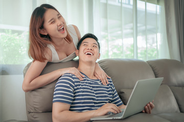 Happy asian couple shopping online using digital tablet with holding credit card and sitting on sofa at home together. Happy lifestyle concept..