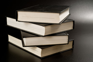Books with black covers shot on a dark background. Background for study, reading and science.