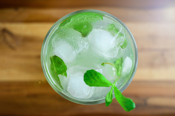 Refreshing alcoholic cocktail Mojito with white rum limes and soda mineral water on wooden board table background. Copy space. Bright summer drink with mint infused alcohol, ice cubes. Shot from top