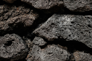 Porous black stones with texture. Close-up. Structure shot with black background. Wallpaper concept.