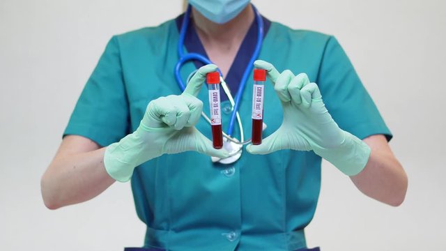 medical doctor nurse woman wearing protective mask and latex gloves - holding blood test tube