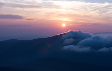 sunset in the mountains, mountains in the clouds in a haze