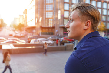 Close up portrait of a man in the background of the urban landscape in the light of sunset. Free space for text.