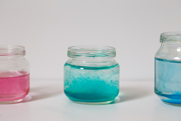 small glass jars with colorful water on a white background