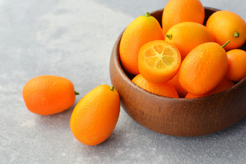 Fresh kumquats in wooden bowl, cut in half. Healthy vegan food. Side view.