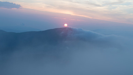 Fototapeta premium sunset in the mountains, mountains in the clouds in a haze