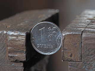 Coin one Russian ruble clamped by a metal vice on both sides. Concept of financial and business problems. The economy is in the grip