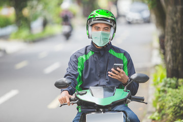 portrait of happy asian man work as a commercial motorcyle taxi driver taking order from his...