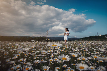 Beautiful brunette woman is enjoying spring in a field of daisies