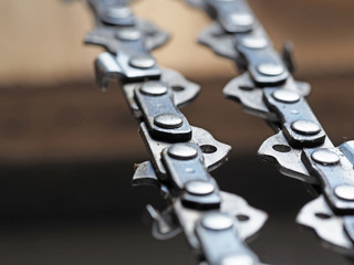 metal chainsaw chain with sharp teeth close-up with blurred background
