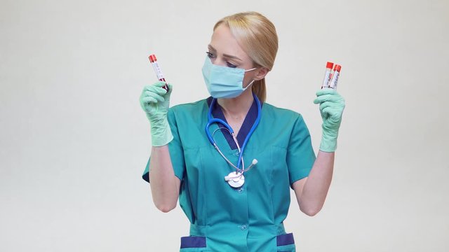 medical doctor nurse woman wearing protective mask and latex gloves - holding blood test tube
