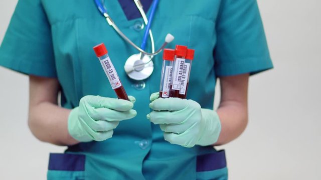 medical doctor nurse woman wearing protective mask and latex gloves - holding blood test tube