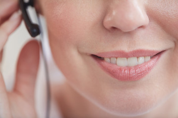 Extreme close up of unrecognizable call center operator wearing headset, focus on pleasant female...