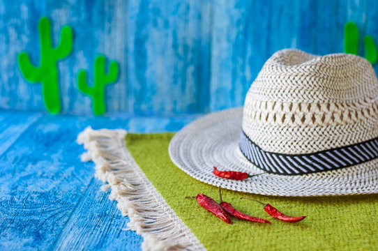 Background to the Cinco de Mayo Mexican Fiesta. Hat, hot chili peppers and green cacti on a bright blue background