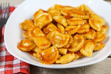 assiette de raviolis à la sauce tomate sur une table en bois