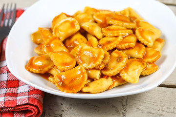 assiette de raviolis à la sauce tomate sur une table en bois