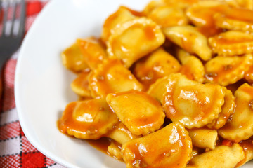 assiette de raviolis à la sauce tomate sur une table en bois
