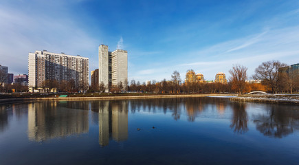 Landscape with lake in the Friendship park in Moscow. Russia. Buildings are reflected in the water