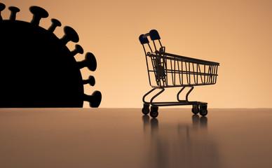 An empty grocery cart with the black silhouette of a coronavirus on the horizon. Concept of the...