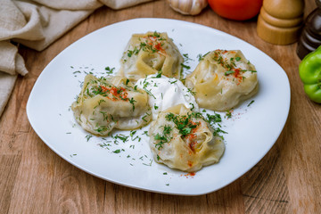 Manty with beef with sour cream on white plate